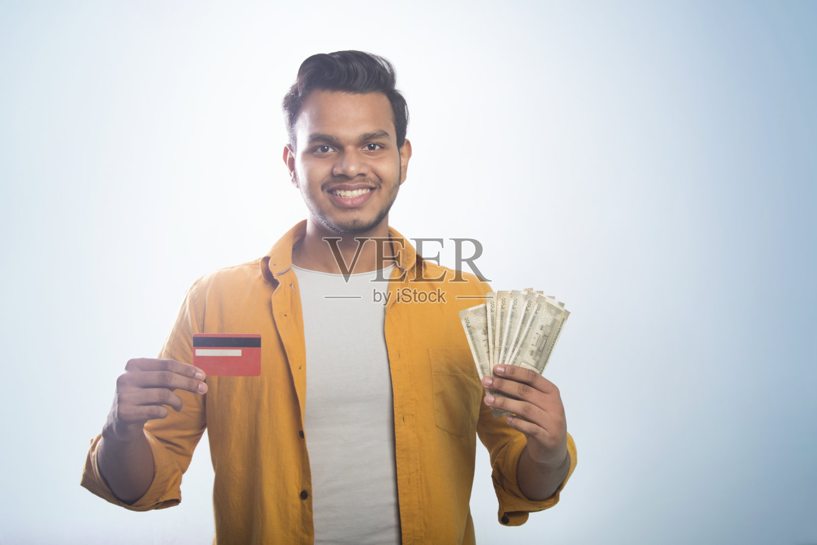 一个站着的年轻人的画像，两只手拿着信用卡和现金照片摄影图片