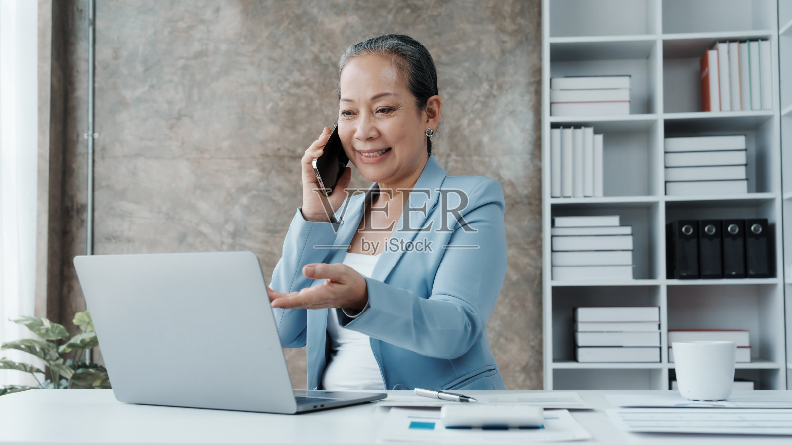 自信的亚洲中国成熟的女商人使用笔记本电脑和台式电脑。照片摄影图片