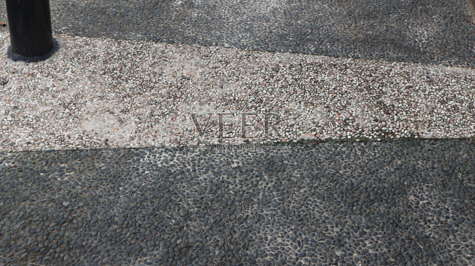 裸露的混凝土骨料，带有不同颜色的鹅卵石。城市公园的砾石地板。照片摄影图片