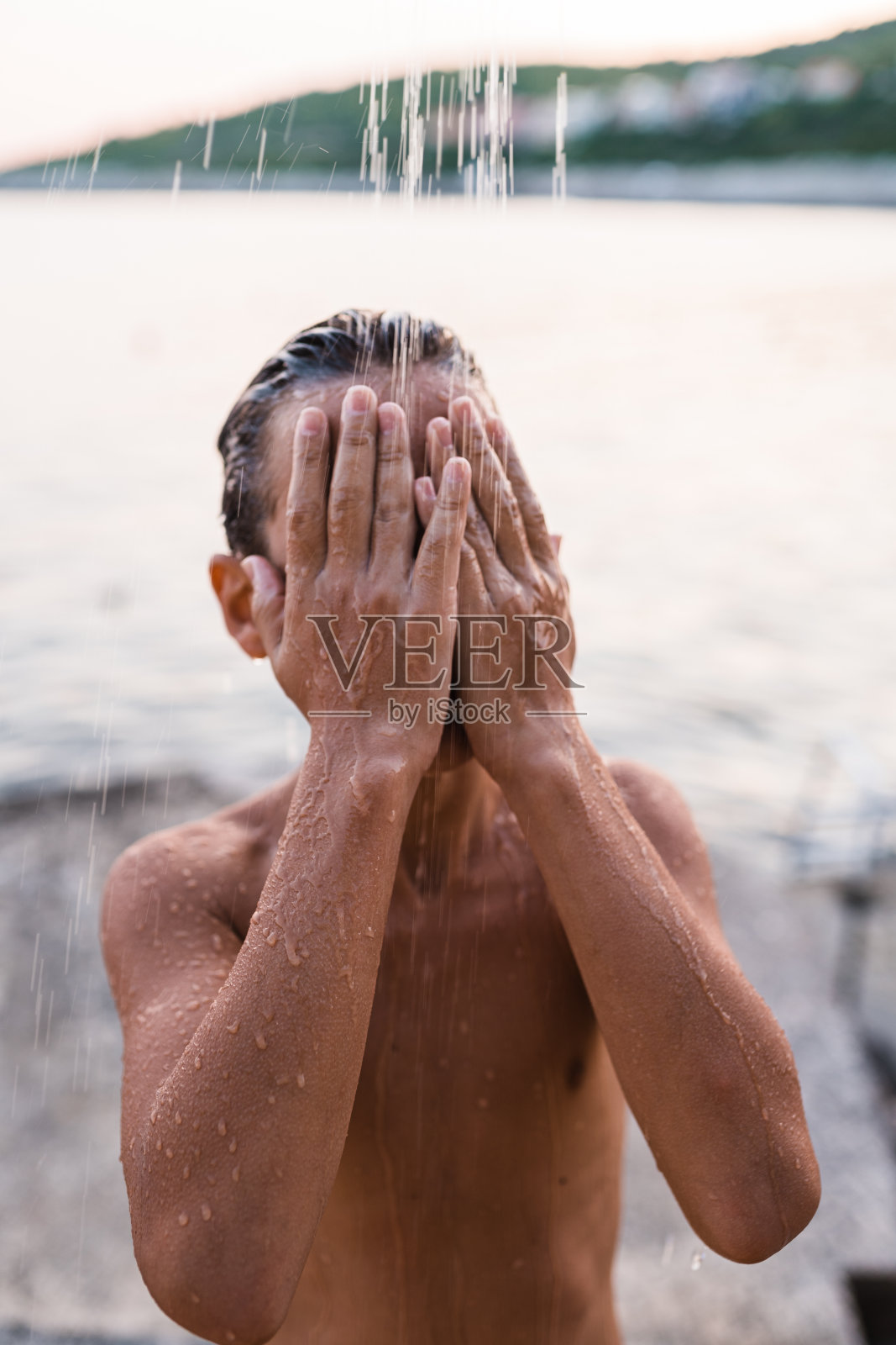 一个十几岁的男孩在海滩上洗澡照片摄影图片