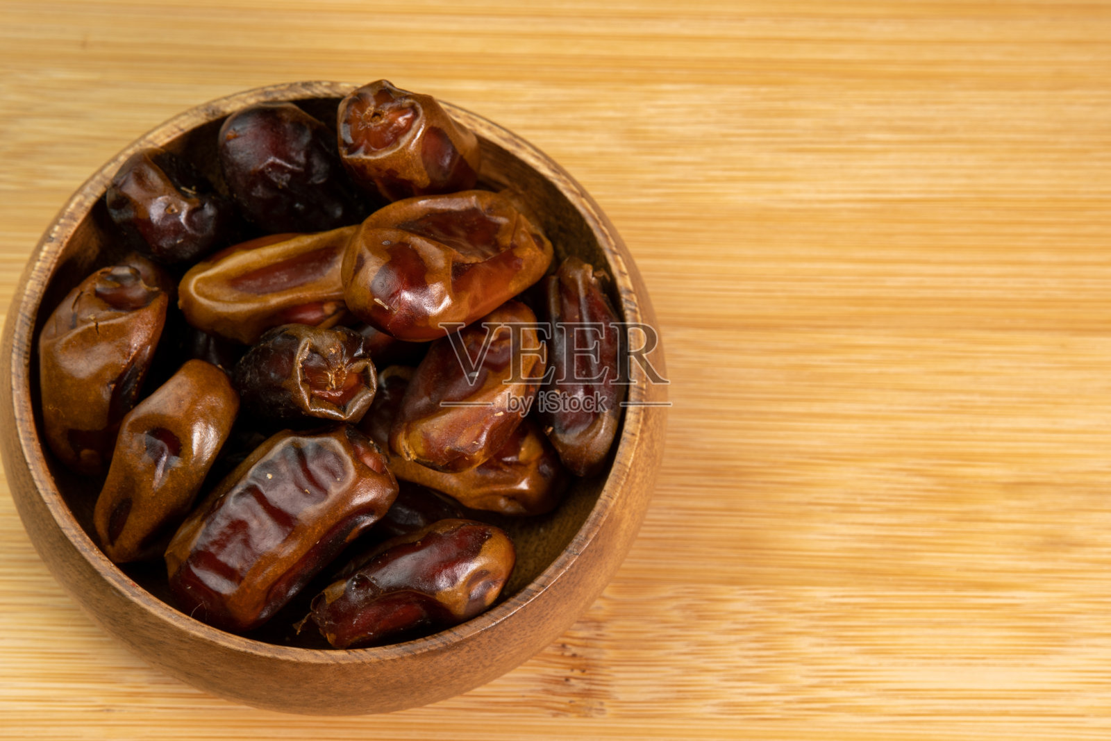 木制背景上木碗里的枣子水果特写。吃干果。素食主义者，素食食品照片摄影图片