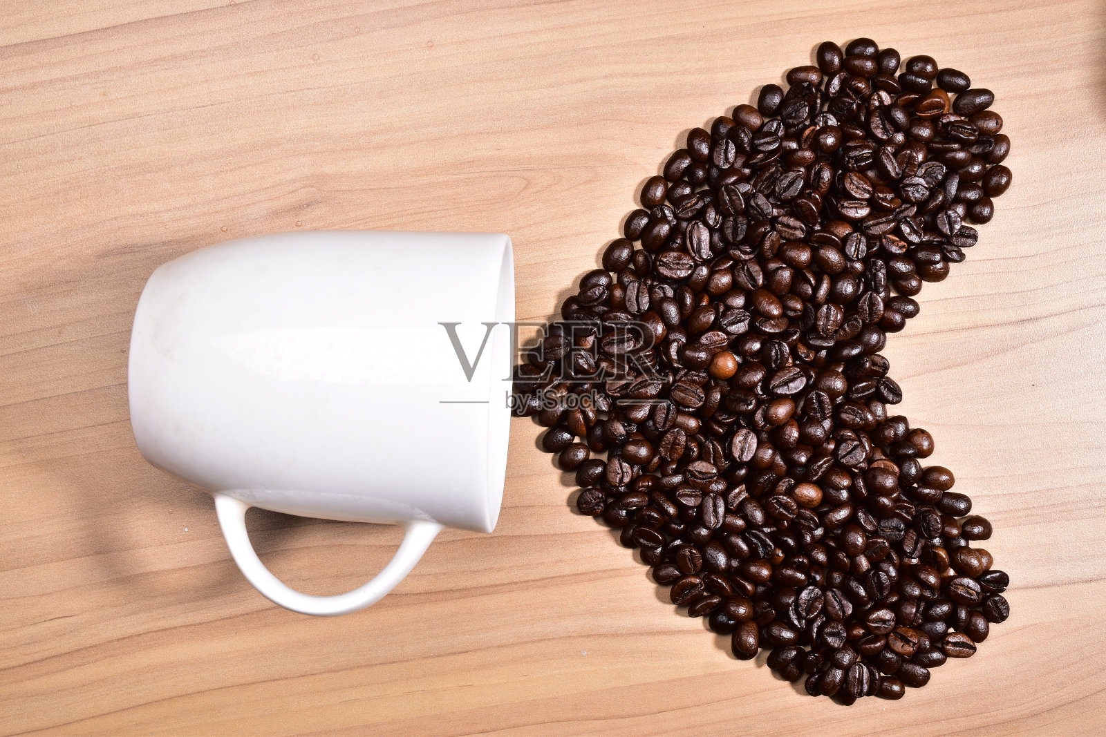 心形烘焙咖啡豆与杯子在桌子上，咖啡日期的概念照片摄影图片