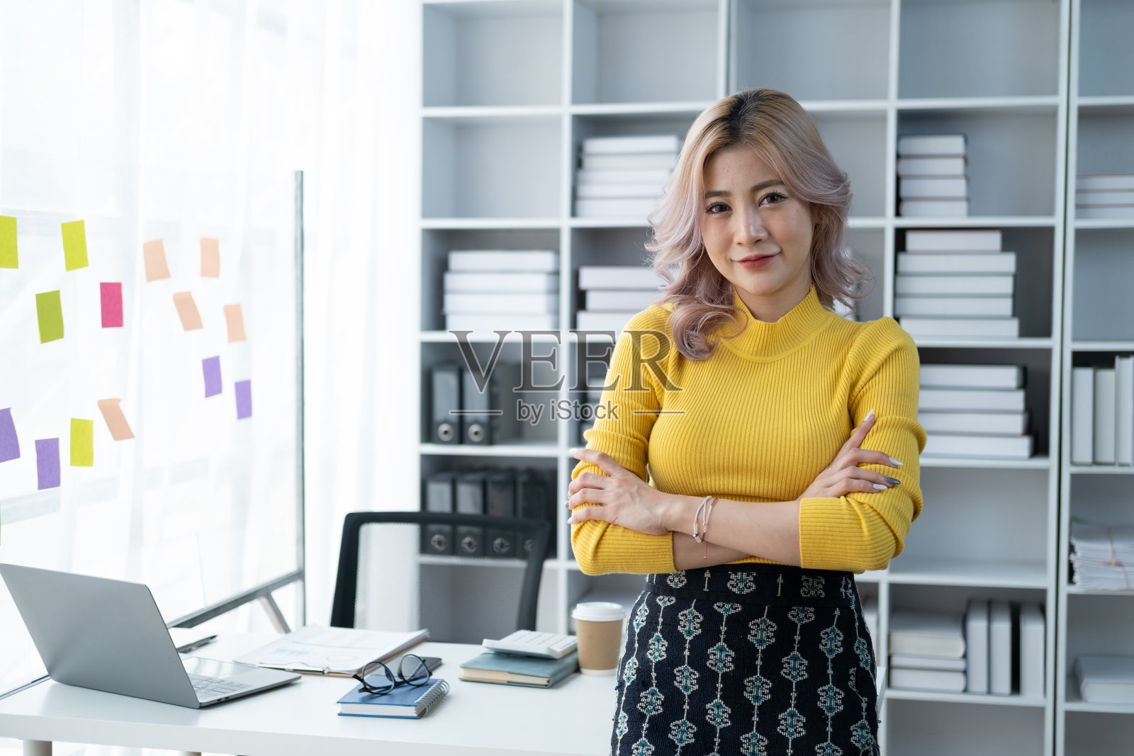 在办公室工作时双臂交叉的迷人女商人。照片摄影图片