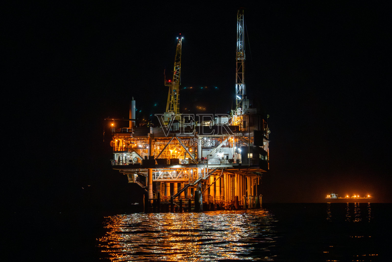 当太阳落在加利福尼亚州亨廷顿海滩上时，一幅令人惊叹的照片捕捉到了一个海上石油钻井平台。照片摄影图片