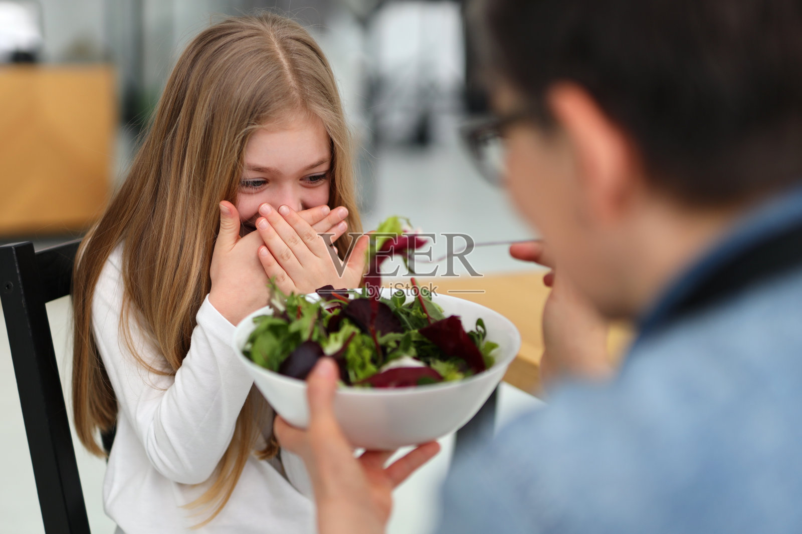 小女孩不想吃沙拉，妈妈正在努力喂。照片摄影图片