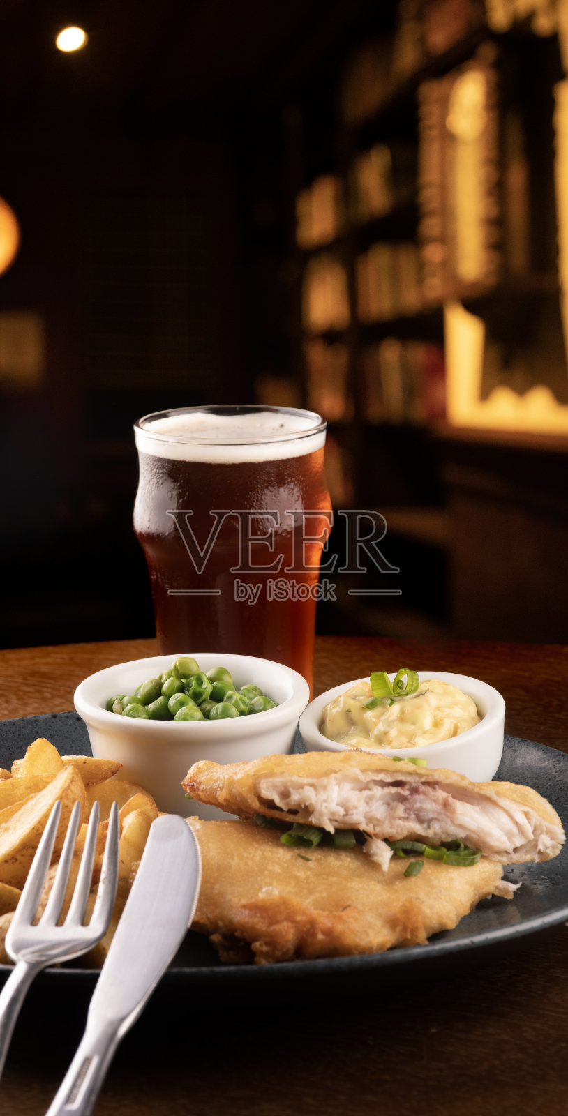 一盘炸鱼薯条和酒吧桌子的特写在背景中模糊了照片摄影图片