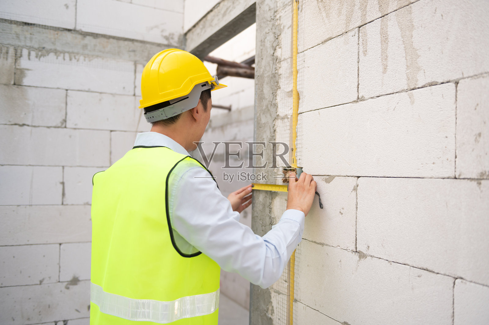 一名亚洲工程师戴着安全帽检查施工现场，分析工程进度照片摄影图片