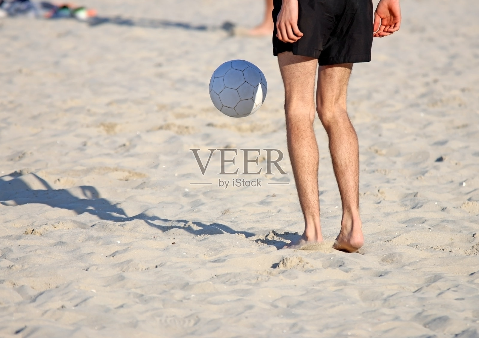 和朋友在沙滩上踢足球，度假。照片摄影图片