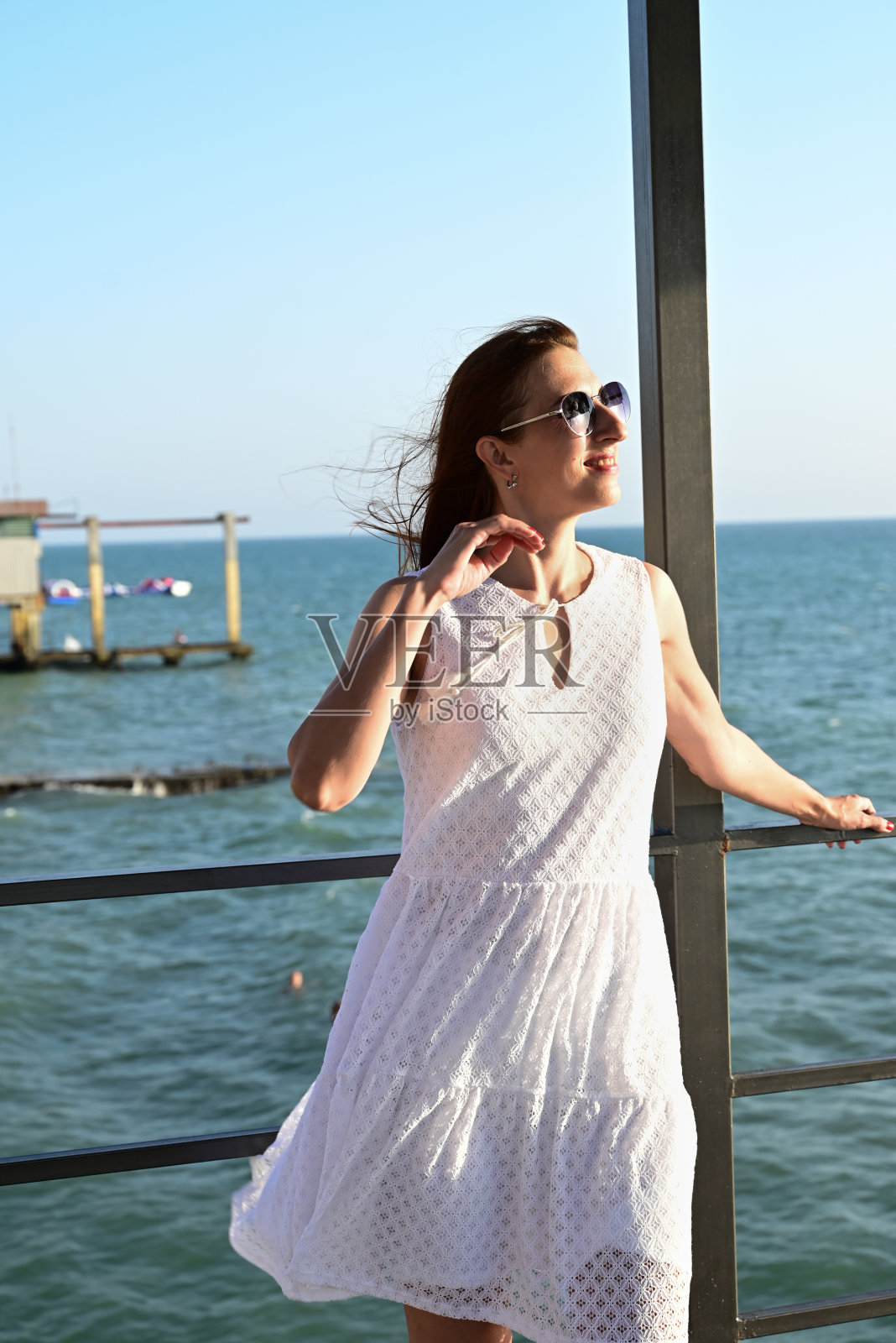 一个穿着夏日白裙的女孩在海边享受生活，眺望远方照片摄影图片