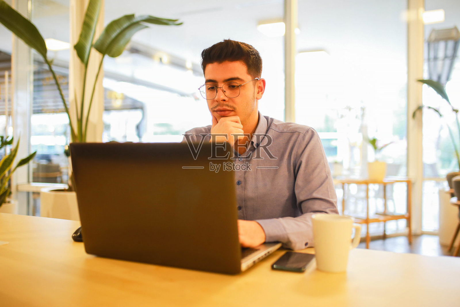 在咖啡馆用笔记本电脑远程工作的年轻人照片摄影图片