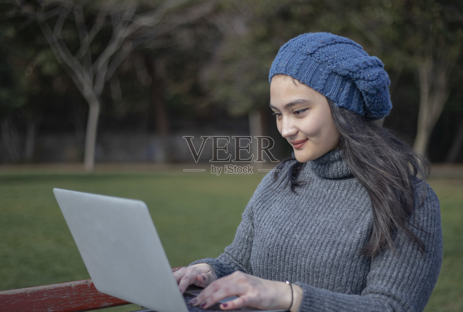 一位年轻的亚洲妇女在公园里摆弄她的电脑照片摄影图片