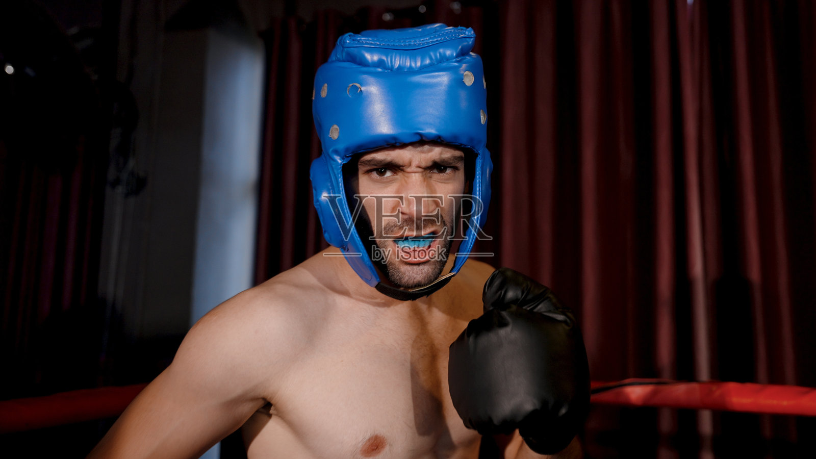 强壮的高加索运动拳击手在拳击场上热身准备拳击。在拳击场上揍对手之前，先树立自信。照片摄影图片