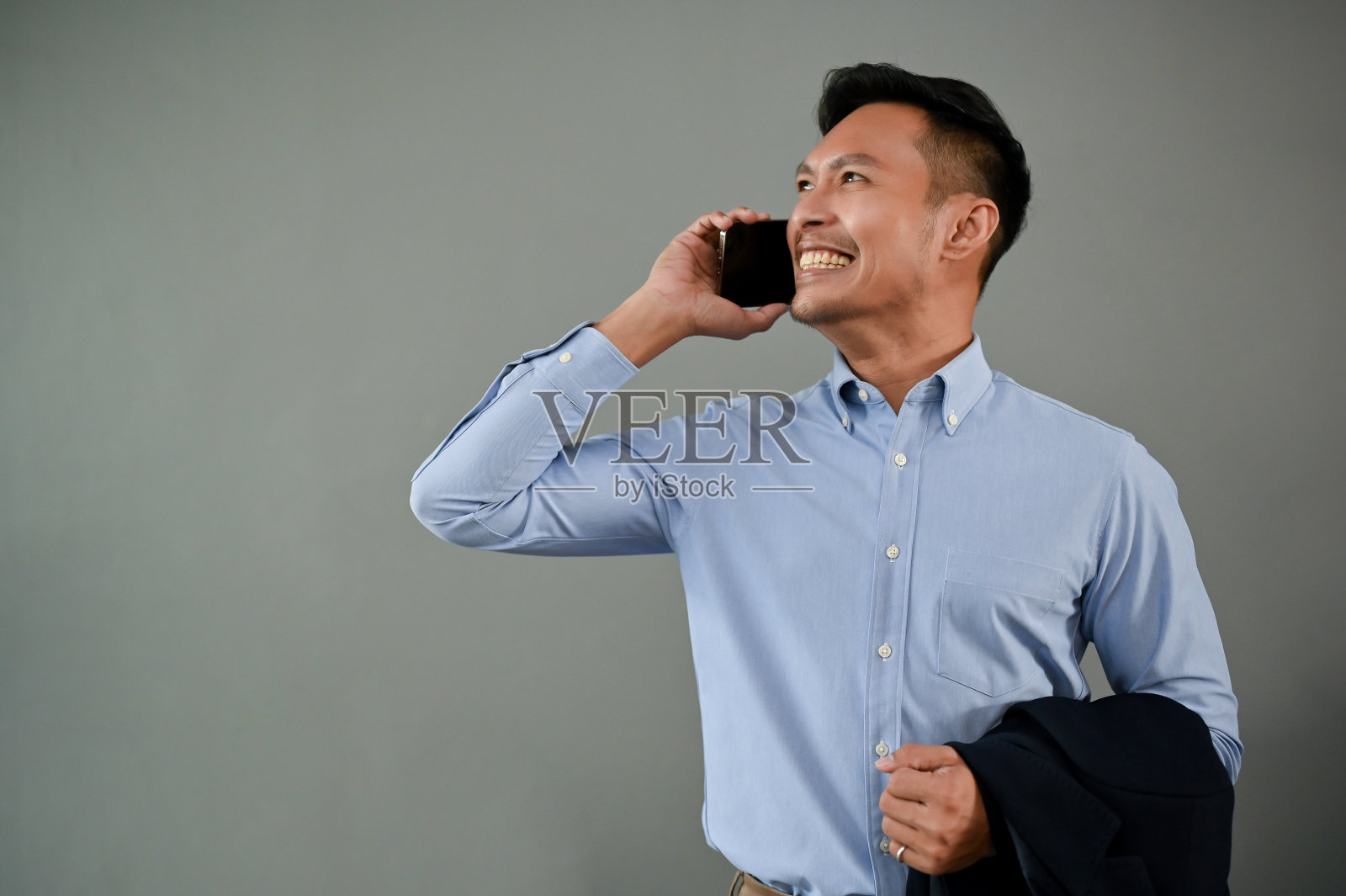 开朗的亚洲商人在电话中交谈，孤立的灰色背景。照片摄影图片