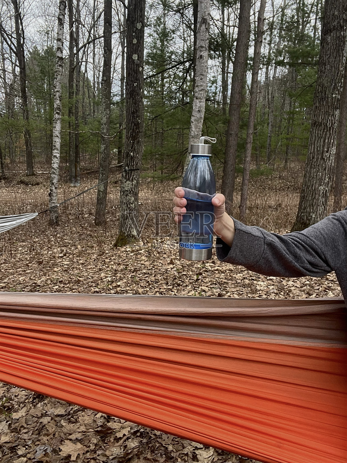 吊床上女子拿着塑料水瓶的部分照片。照片摄影图片