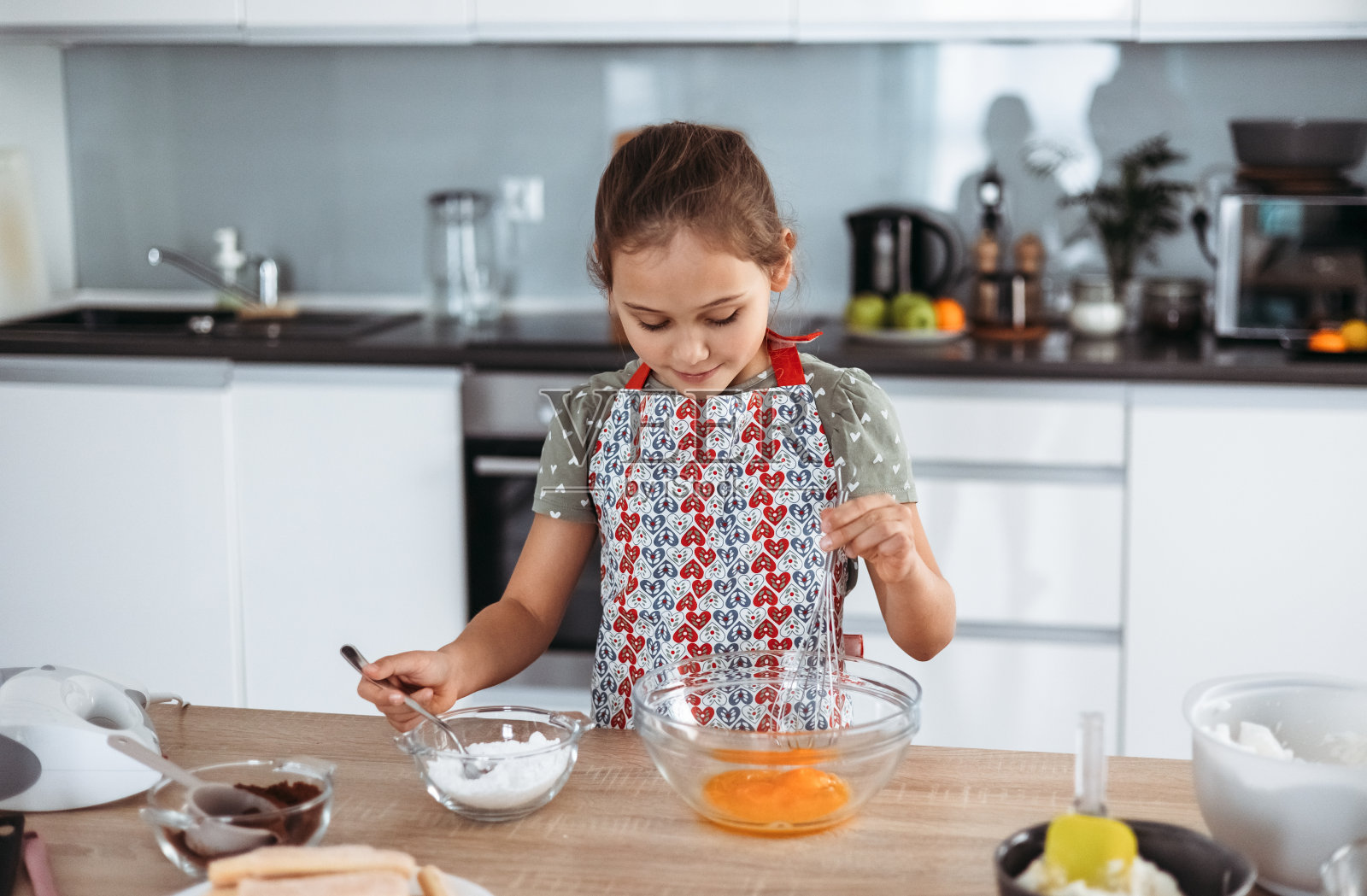 提拉米苏在厨房的制作过程——小女孩用可可和浓咖啡蘸着马斯卡彭奶油制作意大利甜点(一步一步)照片摄影图片