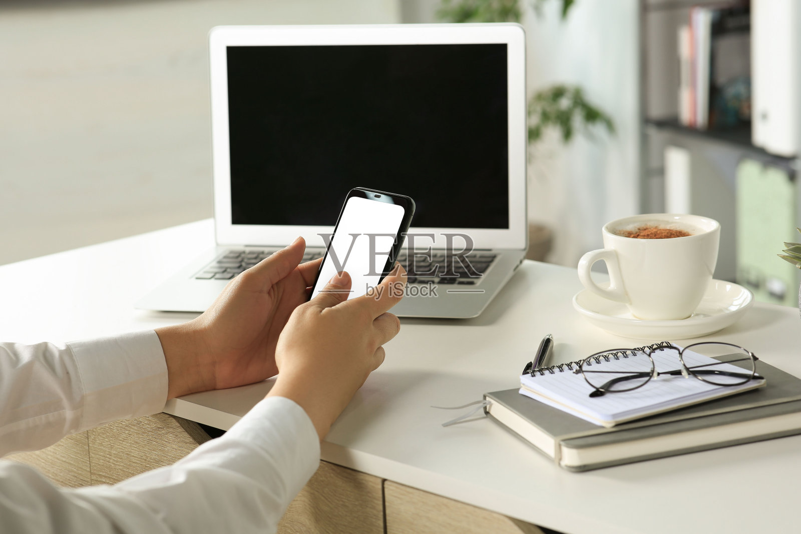 一名女子在室内餐桌上使用智能手机，特写照片摄影图片