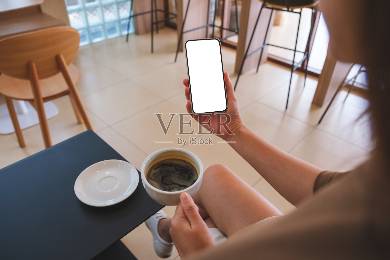 一个女人在咖啡馆喝咖啡，拿着空白桌面的手机的模型图照片摄影图片