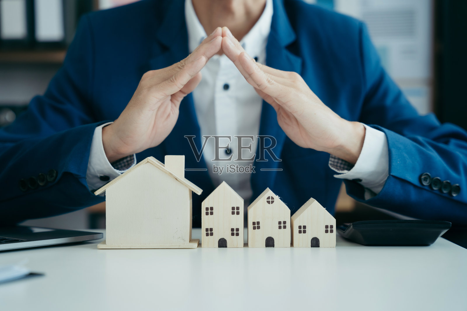 房地产经纪人在办公室向客户提出并咨询决策签订保险合同、房屋模型、有关按揭贷款报价照片摄影图片