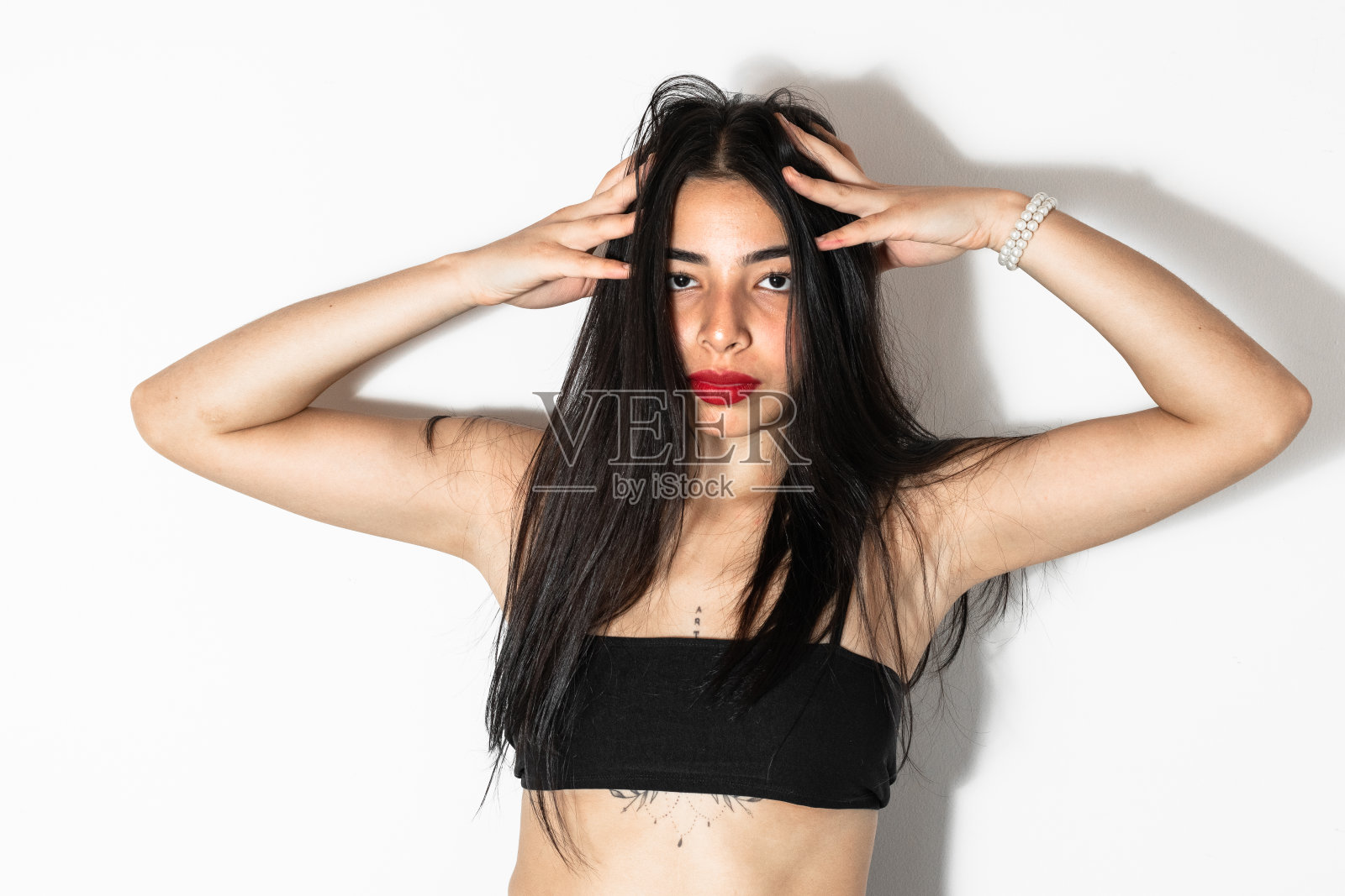 美丽的棕色皮肤的拉丁女人正面摆姿势，双手放在头上照片摄影图片