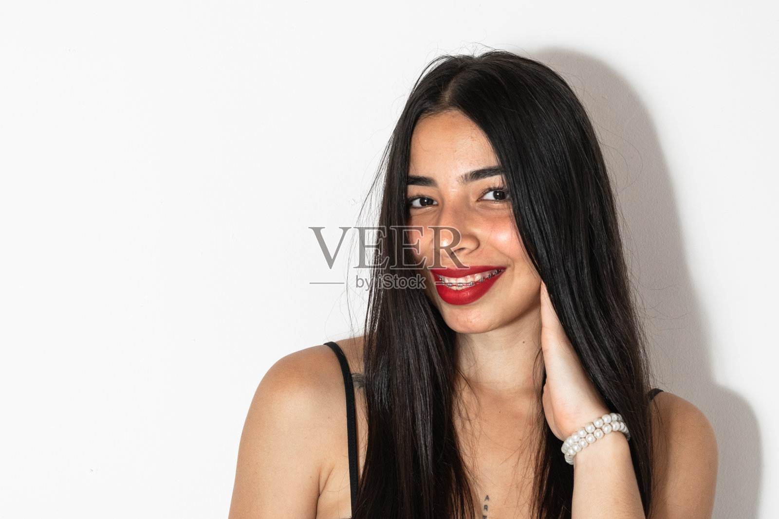 一个美丽的年轻拉丁女人的特写肖像，一只手放在她的脸颊上微笑照片摄影图片