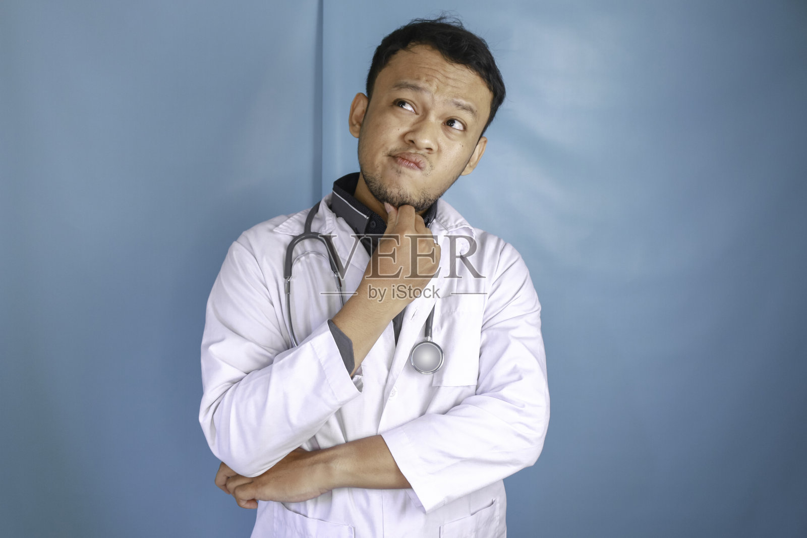 年轻的男医生在孤立的背景下思考一个想法照片摄影图片