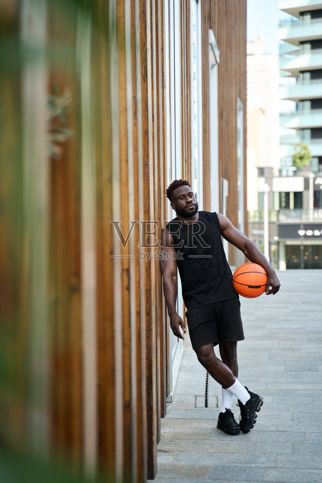 强壮的年轻黑人拿着篮球站在户外。照片摄影图片