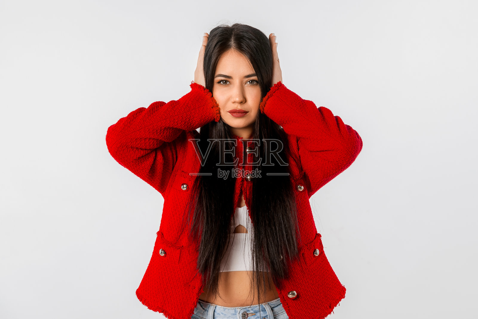 漂亮的年轻女子用手捂住耳朵。不满的女孩咬紧牙关，塞住耳朵，被巨大的声音或噪音惹恼，站在白色的背景上照片摄影图片