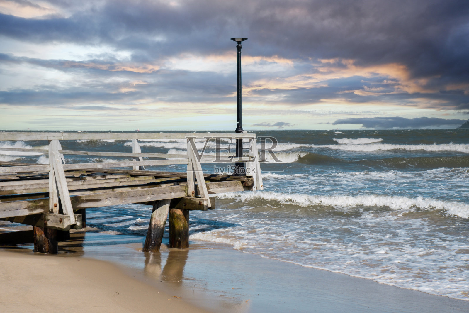 风暴海浪空木码头在戏剧性的蓝天背景。海浪飞溅的海景。波兰格但斯克的沙滩度假胜地。照片摄影图片