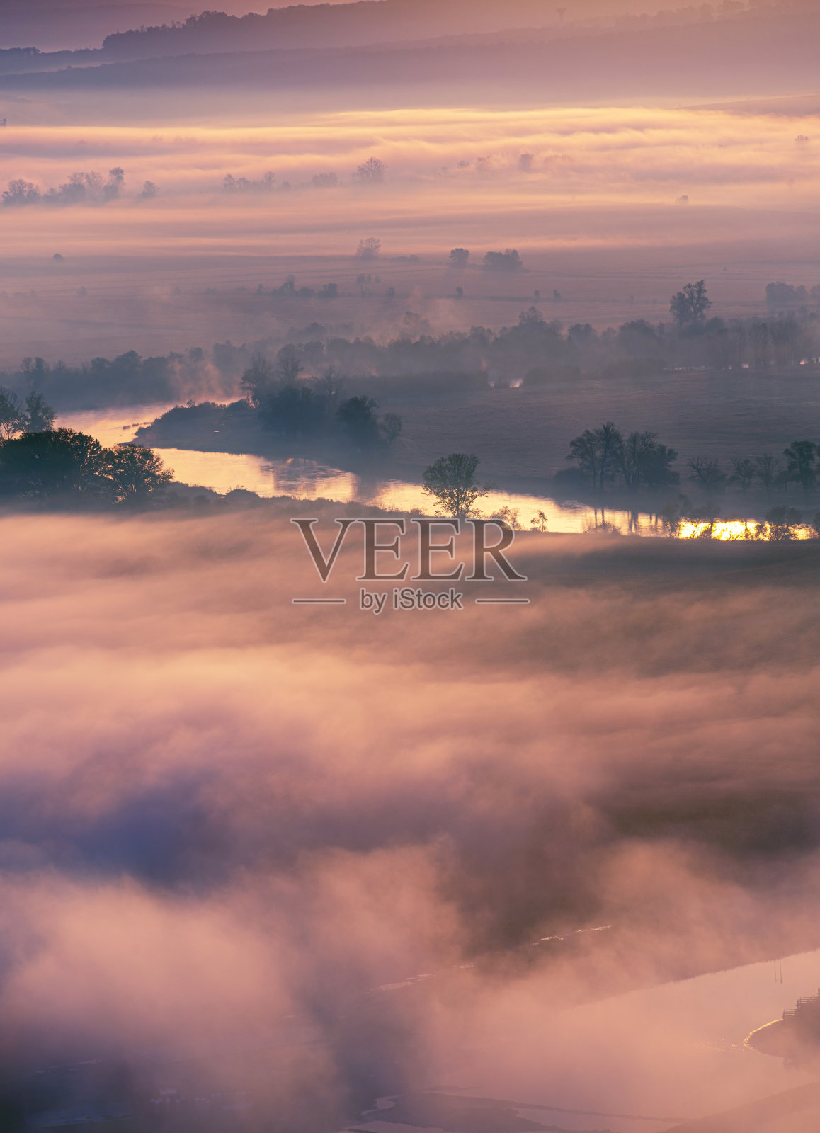 鸟瞰清晨薄雾中的山谷，美丽的高地。低低的云和雾笼罩着沉睡的草地。黎明时分，高山山谷薄雾缭绕。宁静的乡村时光照片摄影图片