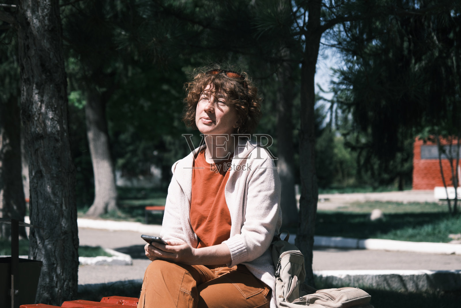 春天的城市公园里，一个女人坐在长椅上打电话照片摄影图片