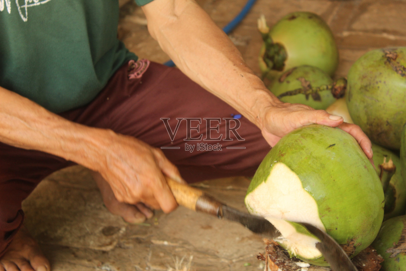 用大砍刀削椰子皮喝水的特写照片摄影图片