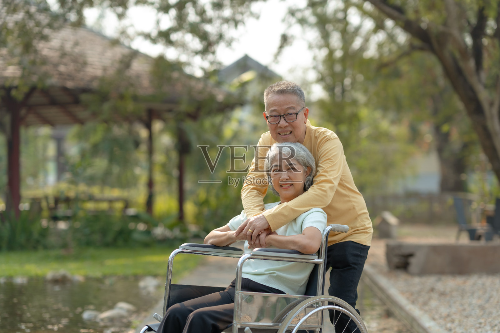 老年夫妇：亚洲夫妇幸福地微笑，彼此表达爱意。亚洲老丈夫照顾并爱着坐在轮椅上的妻子照片摄影图片