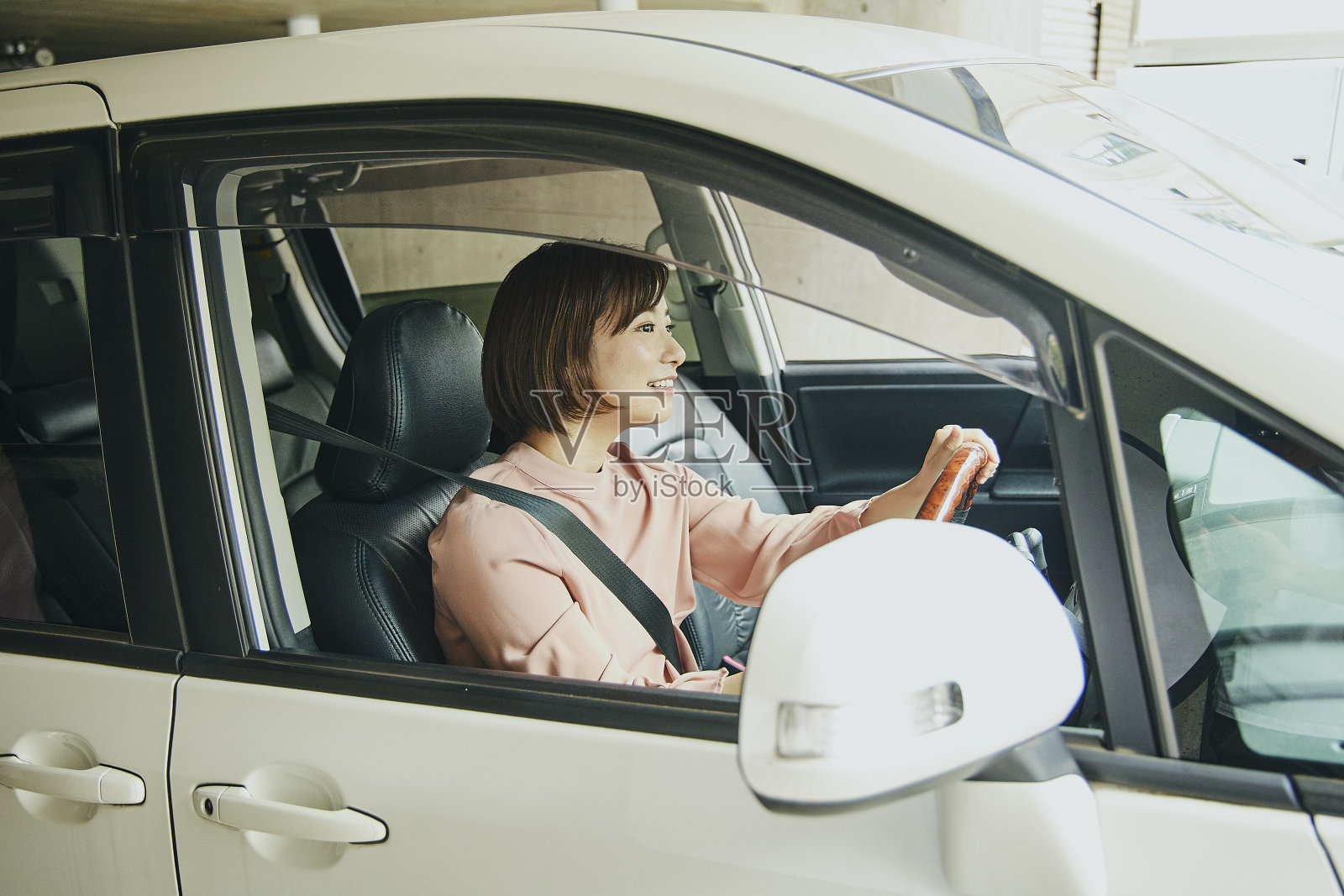 穿粉色衣服开白色车的女人。照片摄影图片