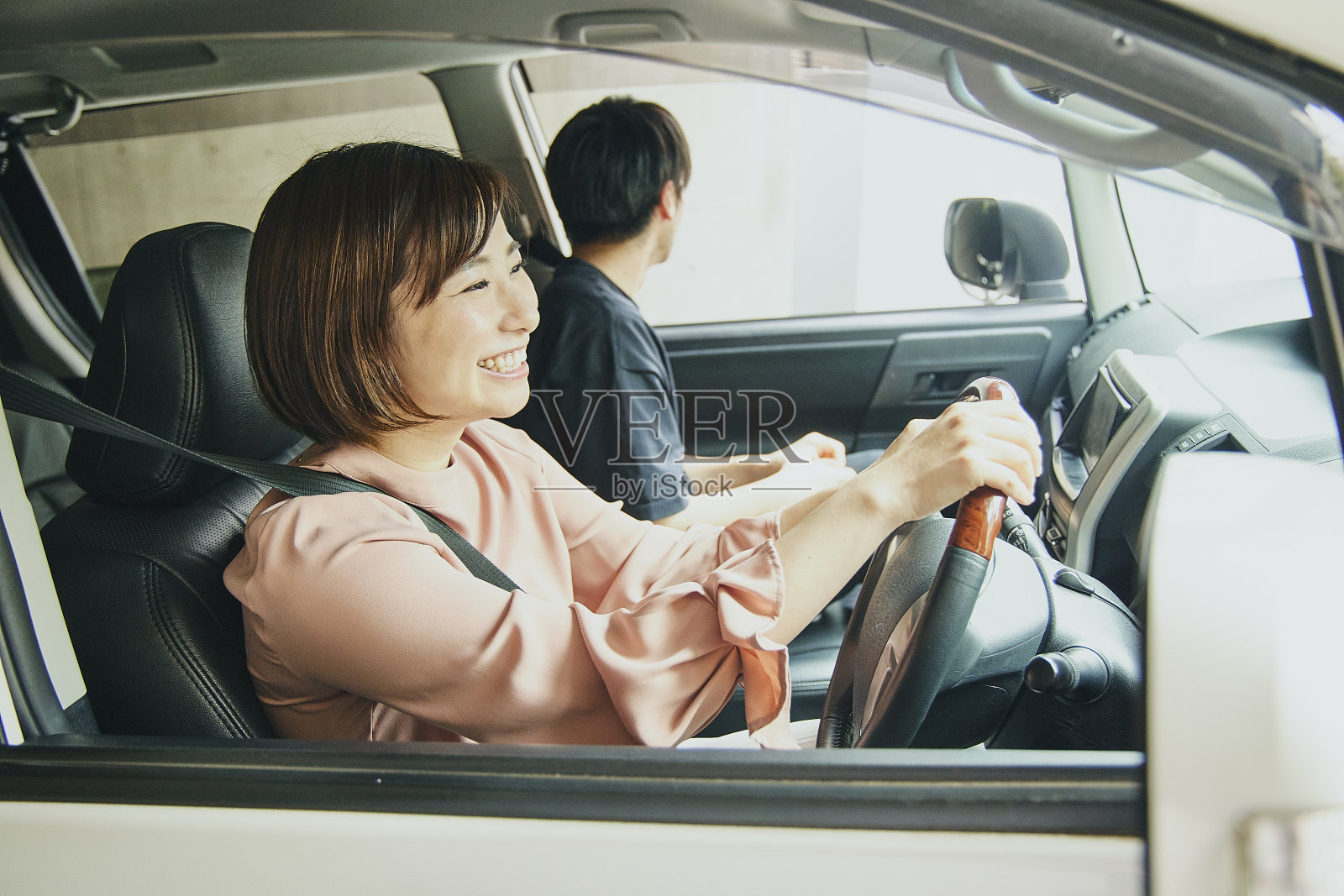 穿粉色衣服开白色车的女人。照片摄影图片