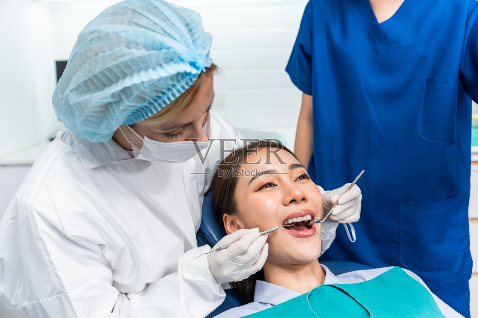 一名白人牙医在牙科诊所为小女孩检查牙齿。美女病人躺在牙科椅上，在医院的牙科预约服务中接受医生的牙科治疗照片摄影图片