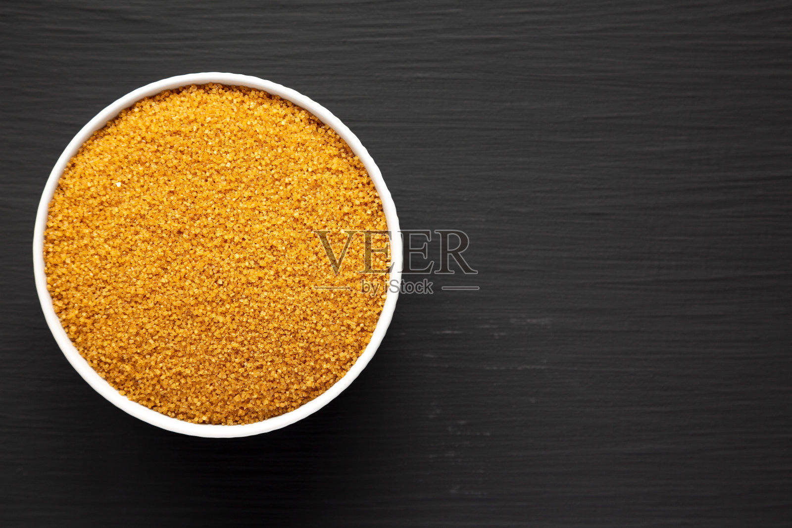 黑面上的棕色德米拉糖碗，俯视图。平躺，头顶，从上面看。文本空间。照片摄影图片