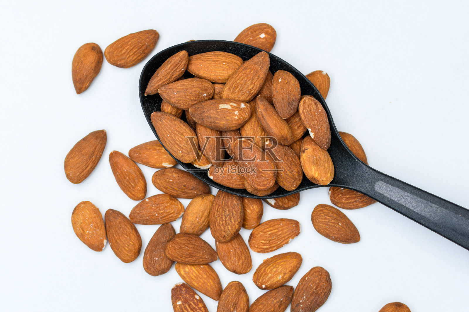 加州杏仁带皮，用黑色厨房勺子盛着照片摄影图片