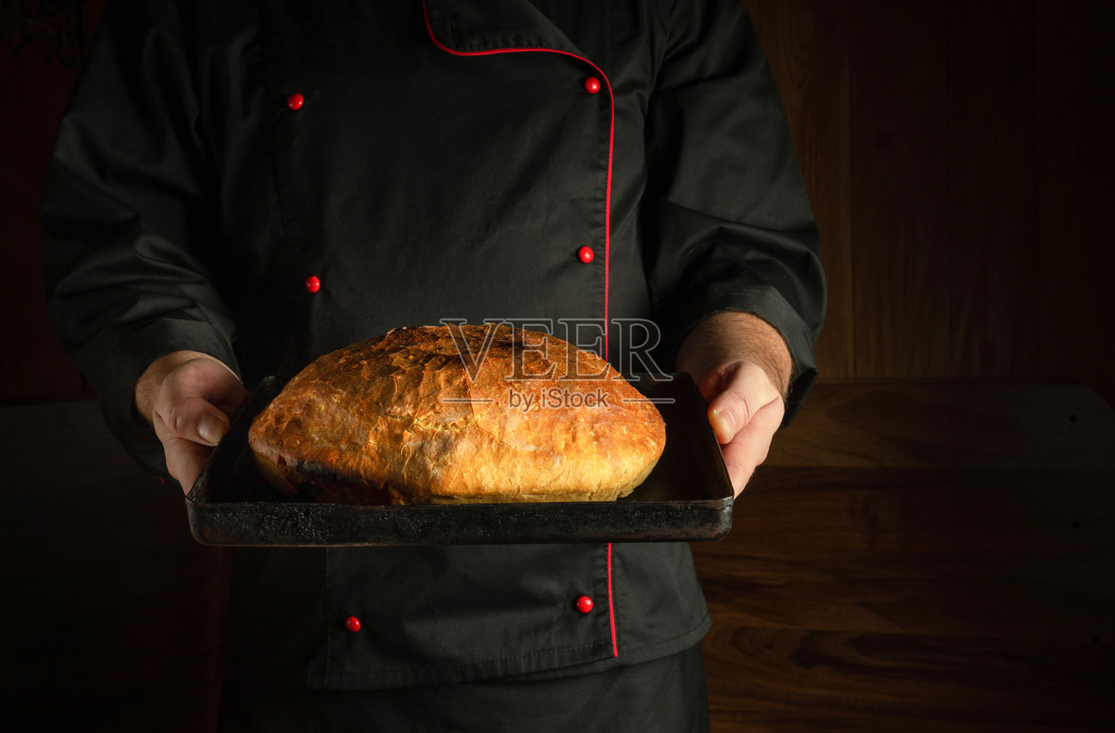 厨师正把新鲜的黑麦面包放在平底锅上。副本的空间。在家烤面包的概念照片摄影图片