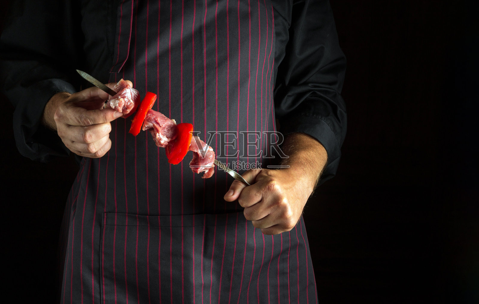 厨师手里拿着烤肉，烤肉串上有生牛肉和蔬菜。亚洲民族菜照片摄影图片