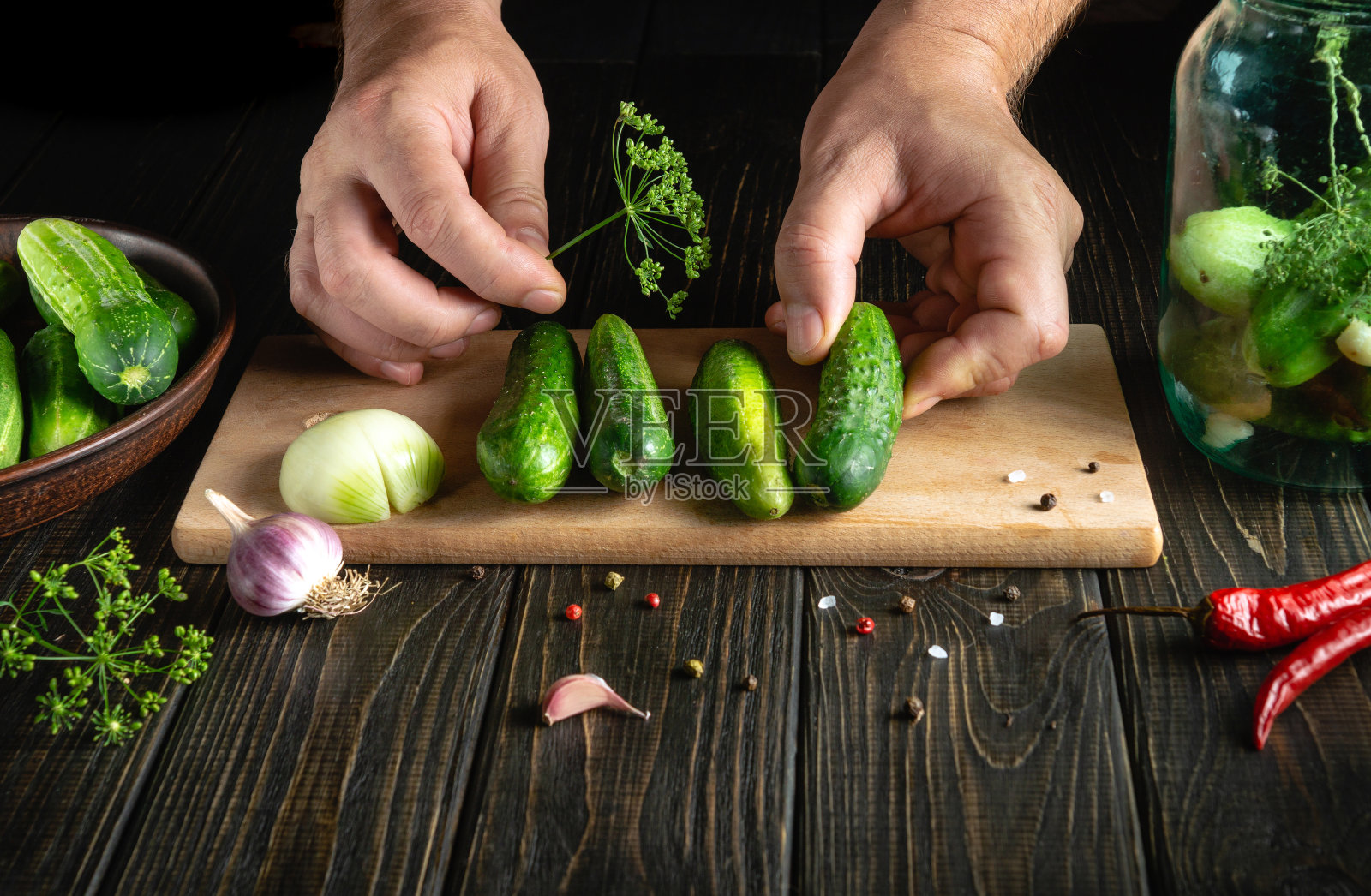 挑选的黄瓜由厨师的手保存或腌制在一个罐子里。厨房餐桌上的工作环境。照片摄影图片