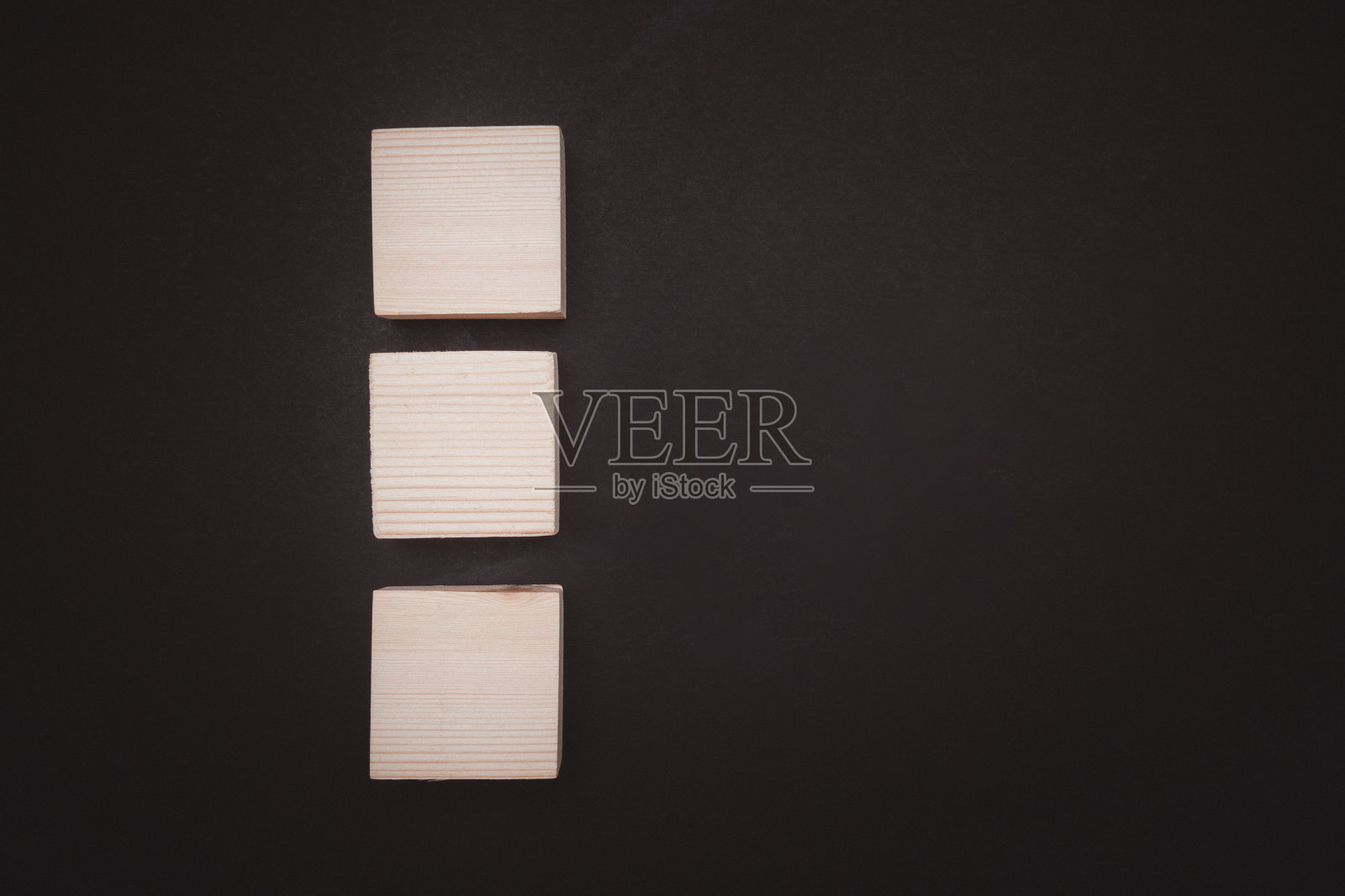 黑色背景上空白的三个木制立方体的俯视图，并留出文字空间。照片摄影图片