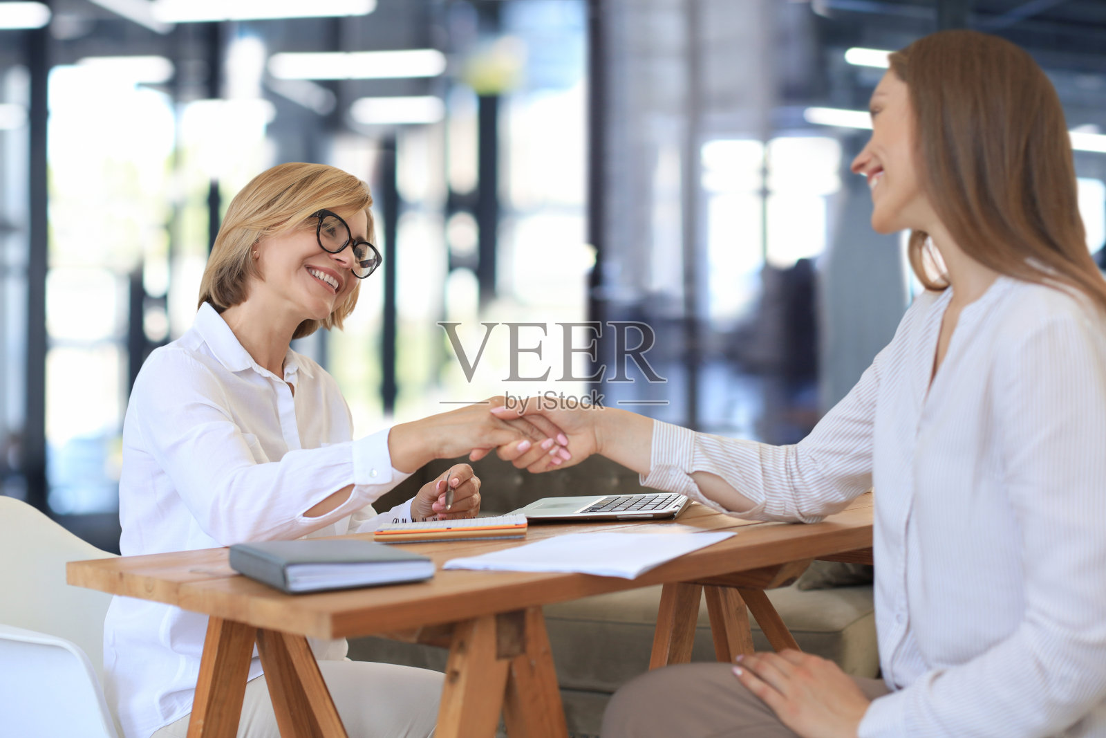 开朗的女心理医生在会诊后与病人感激地握手。照片摄影图片