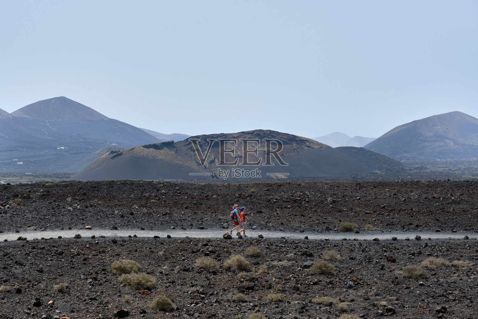 母子俩在加那利群岛兰萨罗特岛的火山中徒步旅行。照片摄影图片