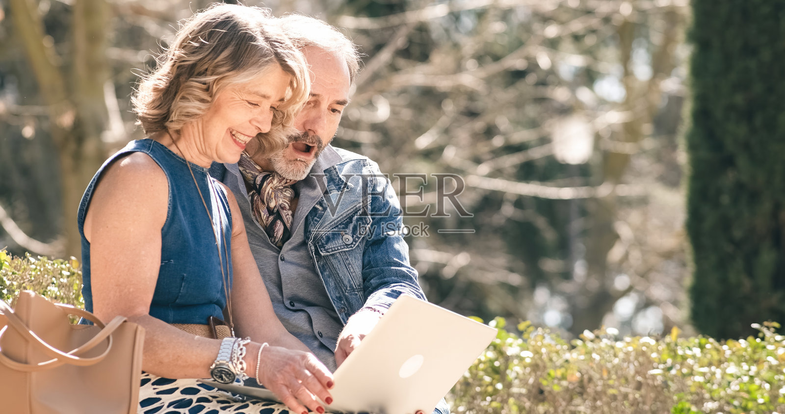 一对成熟的夫妇坐在石凳上使用笔记本电脑照片摄影图片