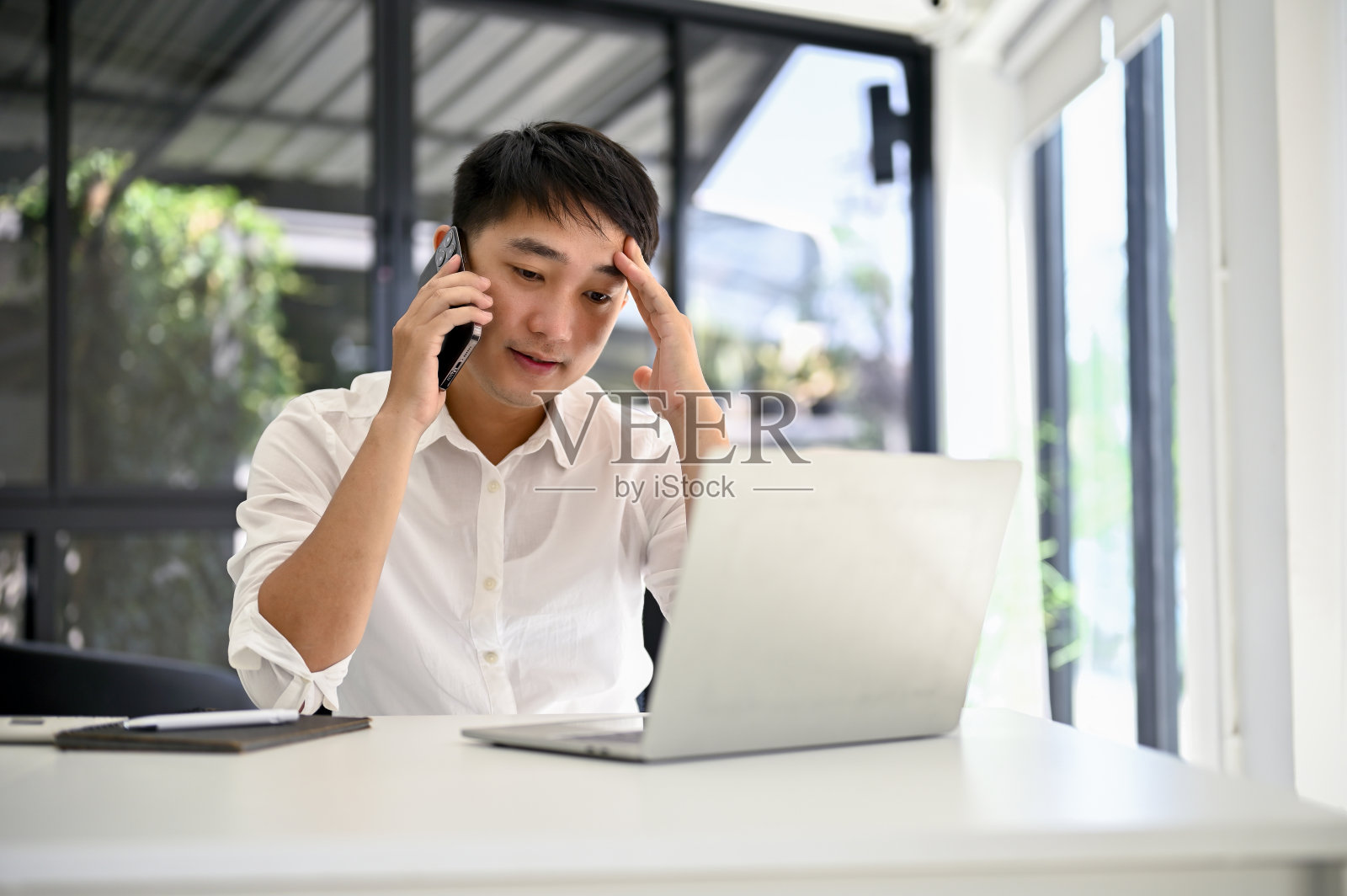 紧张的亚洲商人在电话中与他的商业客户处理业务照片摄影图片