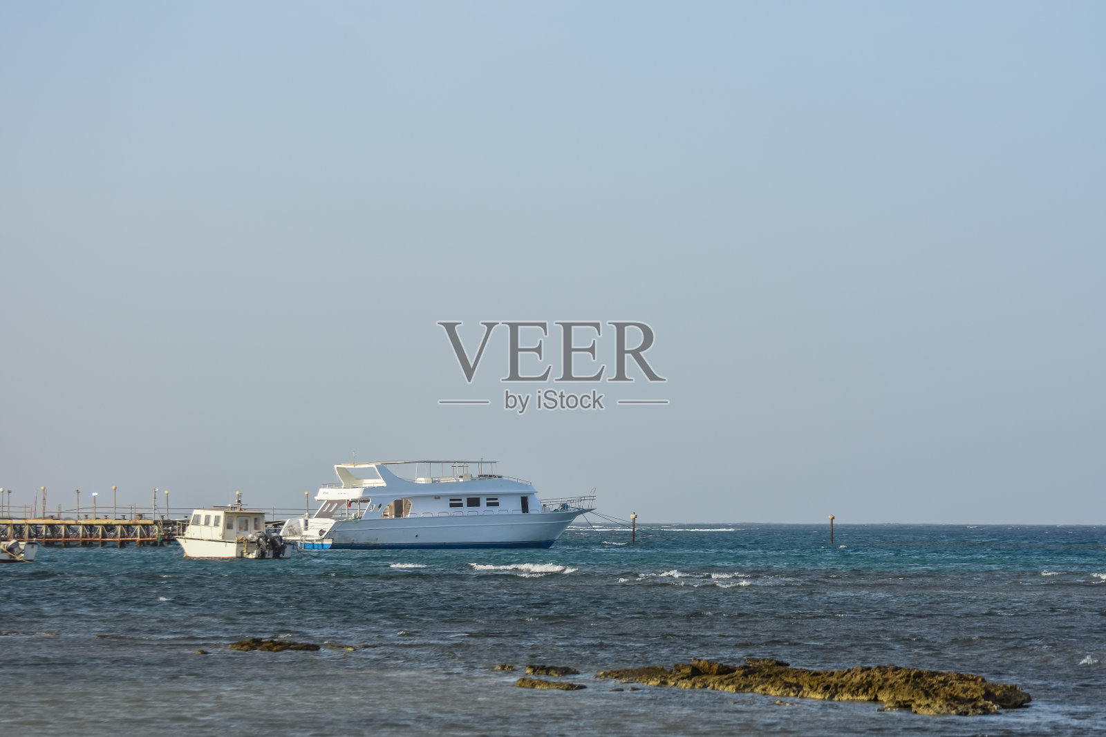 白色的船停在码头上，在蓝天下的红海里照片摄影图片