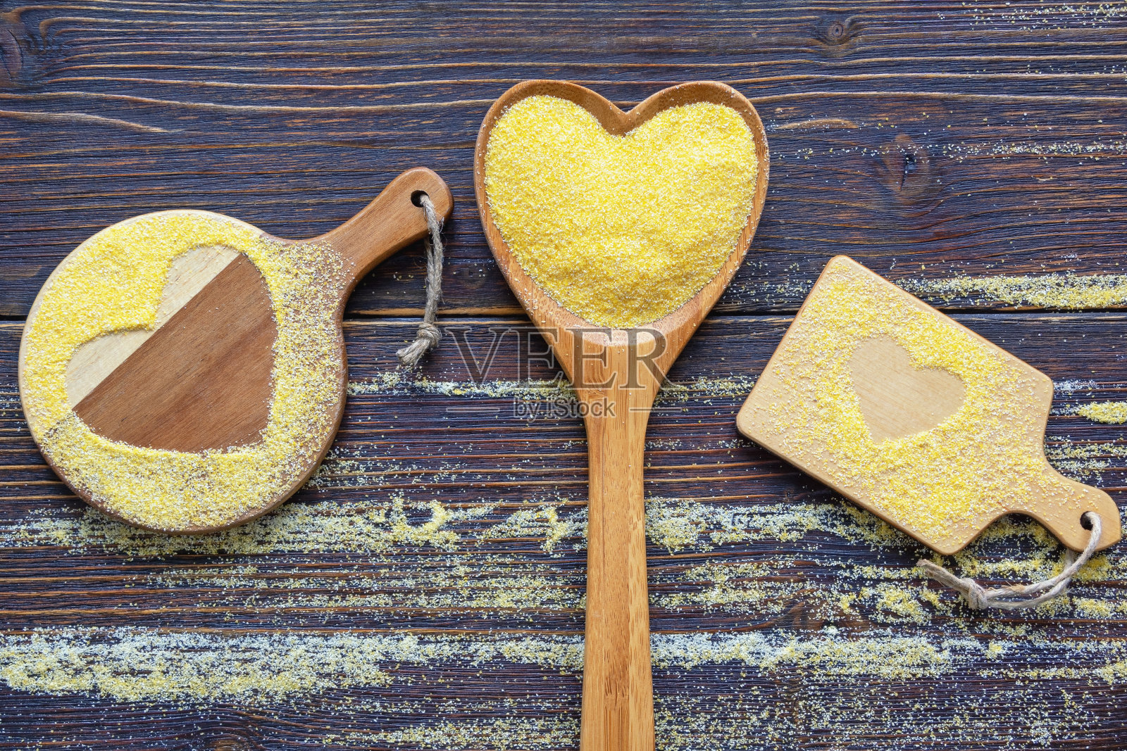 用心形木勺盛的玉米粉。黑色质朴的桌子上的菜板和玉米粉。本空间照片摄影图片