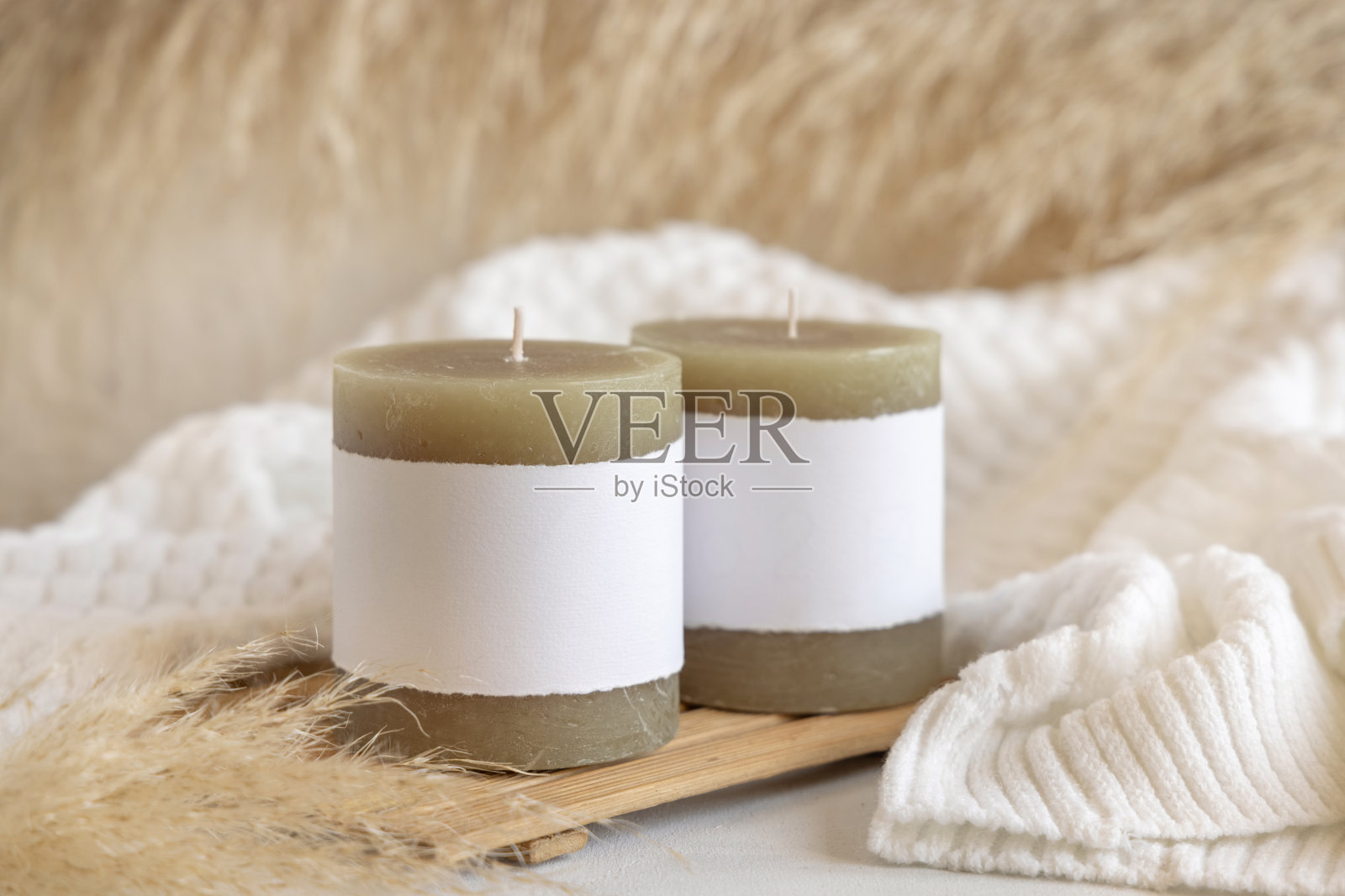 在潘帕斯草原和舒适的毛衣旁的木托盘上有标签的蜡烛，近距离，模拟照片摄影图片
