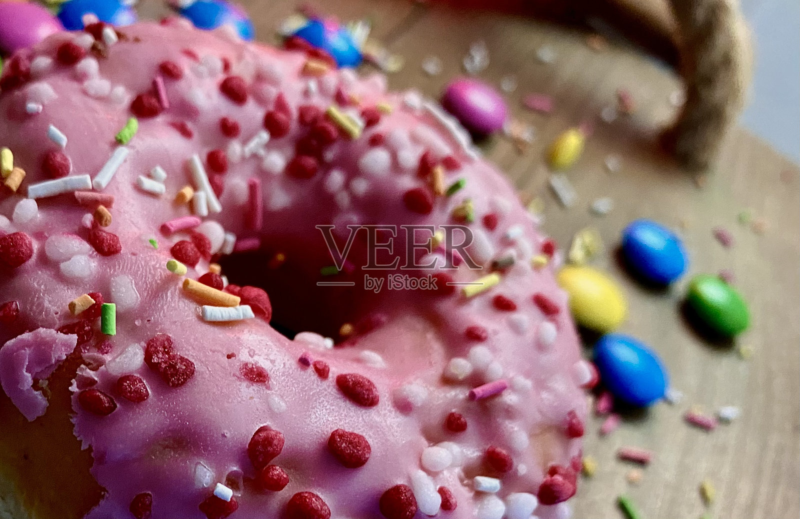 甜甜圈与彩色糖衣在粉红色照片摄影图片