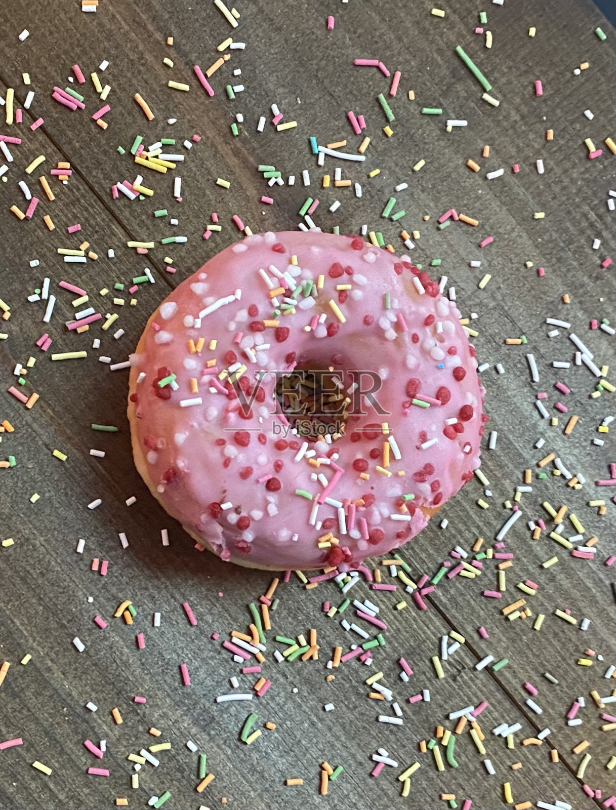 甜甜圈与彩色糖衣在粉红色照片摄影图片
